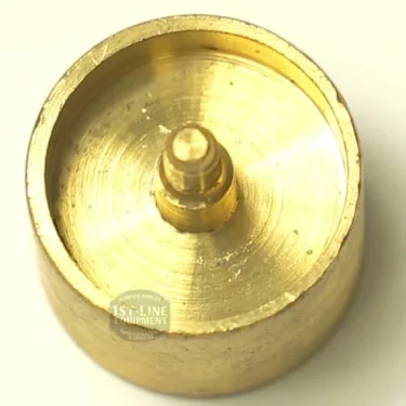 A round, golden brass VBM.81 VALVE BODY espresso machine part features a raised central peg and smooth, shiny finish, shown from above on a light background. © 2025 1st-line.com