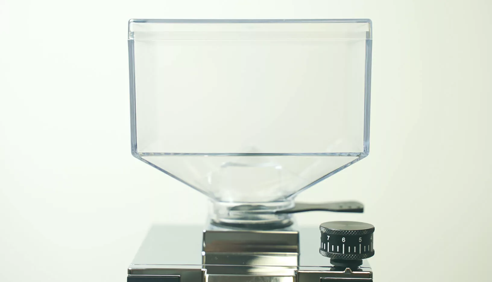 A transparent hopper sits atop the shiny Eureka Oro Mignon XL Espresso Coffee Grinder, featuring a visible black numbered grind size dial on the right, set against a plain, light background. © 2025 1st-line.com