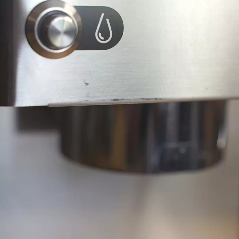 Close-up of the stainless steel water dispenser button with droplet icon, indicating water flow on a (SOLD) SIDEWALK SALE - 2016 Lelit Victoria PL91T PID Single Boiler Espresso Machine (returned & refurbished) E111; part of the spout is visible. © 2025 1st-line.com