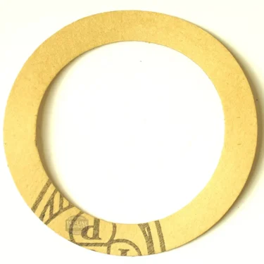 The GI..54 PAPER PISTON GASKET SUPPLEMENT 71x55x0.5 mm is a plain, circular paper gasket ring with part of a black printed design visible on the lower left, shown on a white background. © 2025 1st-line.com