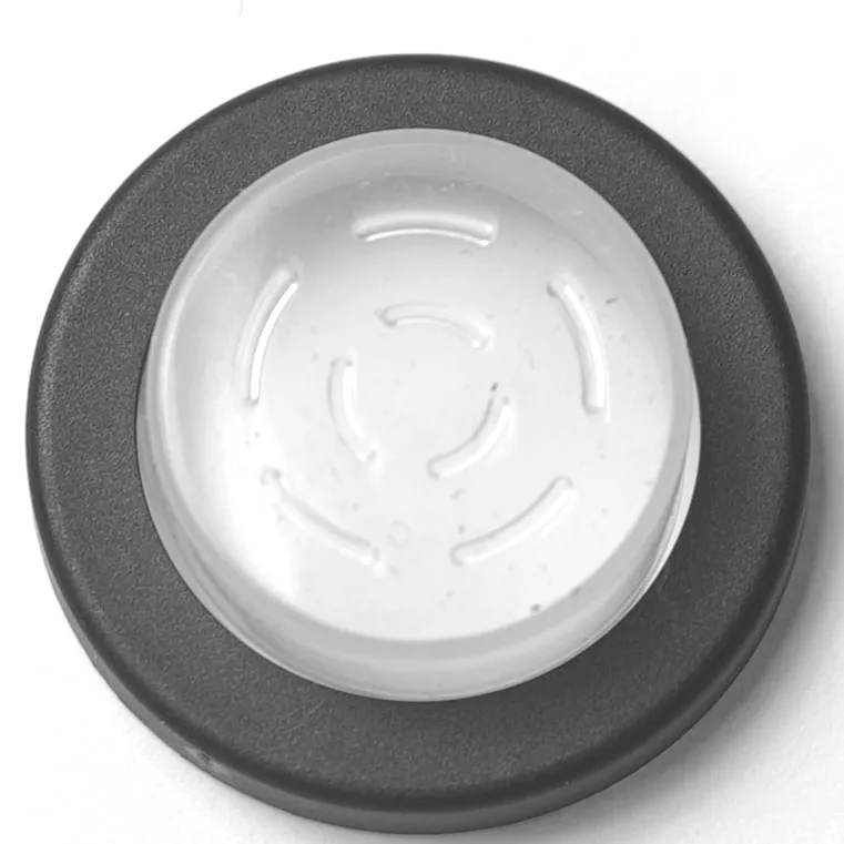 A black circular button with a raised transparent center featuring curved, indented lines in a circular pattern, resembling the V.4331 YELLOW MOMENTARY PUSH SWITCH, is set against a white background. © 2025 1st-line.com
