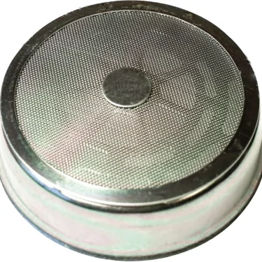 A close-up of a Faema stainless steel espresso machine filter basket with a fine mesh bottom and ridged edge, paired with the Faema NanoQuartz Convex Spokes Dispersion Screen for optimal extraction. © 2025 1st-line.com