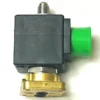 A close-up of the Gaggia 115V 8W 3-WAY ODE SOLENOID shows its black rectangular housing, brass base, metal top connector, and green side connector against a white background. © 2025 1st-line.com