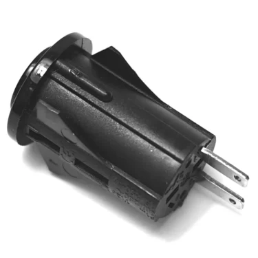 A close-up of the V.4217 16mm BLACK MOMENTARY PUSH-BUTTON shows its cylindrical shape and two metal prongs for electrical connections, angled against a white background. © 2025 1st-line.com
