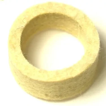 A close-up photo of the SM..54 LEVER GROUP PISTON ROD WASHER, a thick, circular beige felt washer with a hollow center, displayed against a white background. © 2025 1st-line.com