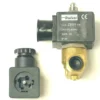A V.1457 24Vac 3-WAY 1/4x1/4 9W Parker solenoid with brass body and black ZB09 coil sits beside a disconnected black connector showing its metal terminals. © 2025 1st-line.com