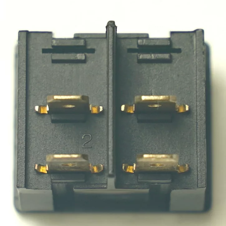 Close-up of a black plastic connector with four gold terminals, marked 2, placed beside a V.4348 GREEN ROCKER SWITCH. © 2025 1st-line.com