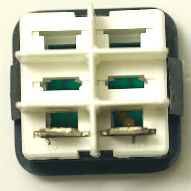 Close-up of the V.4349 BLACK SWITCH: a white plastic electrical connector with four square slots (two with metal contacts), mounted on a black base and viewed from above against a light background. © 2025 1st-line.com