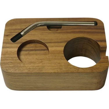 The 1st-line Italian Walnut Wood Tamping Station is rectangular, features two circular compartments and a groove, and elegantly holds a curved metal pipe or tool across the top. © 2025 1st-line.com