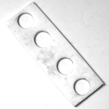 The S..221 PTFE RESISTANCE GASKET 68x55x3mm is a rectangular white plastic gasket with four evenly spaced circular holes in a row, shown on a white surface. © 2025 1st-line.com