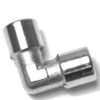 The V.1867 1/8F Elbow Fitting features a shiny metallic finish, a 90-degree angle, and cylindrical openings on both ends, shown against a white background. © 2025 1st-line.com