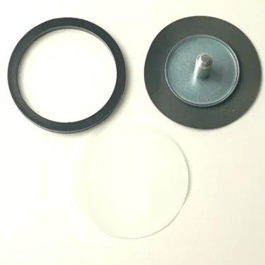 Three circular objects on a white background: a black ring, a metal disc with bolt labeled V..865 3/8 PUMP FILTER, and a clear round sheet, arranged in a rough triangle. © 2025 1st-line.com