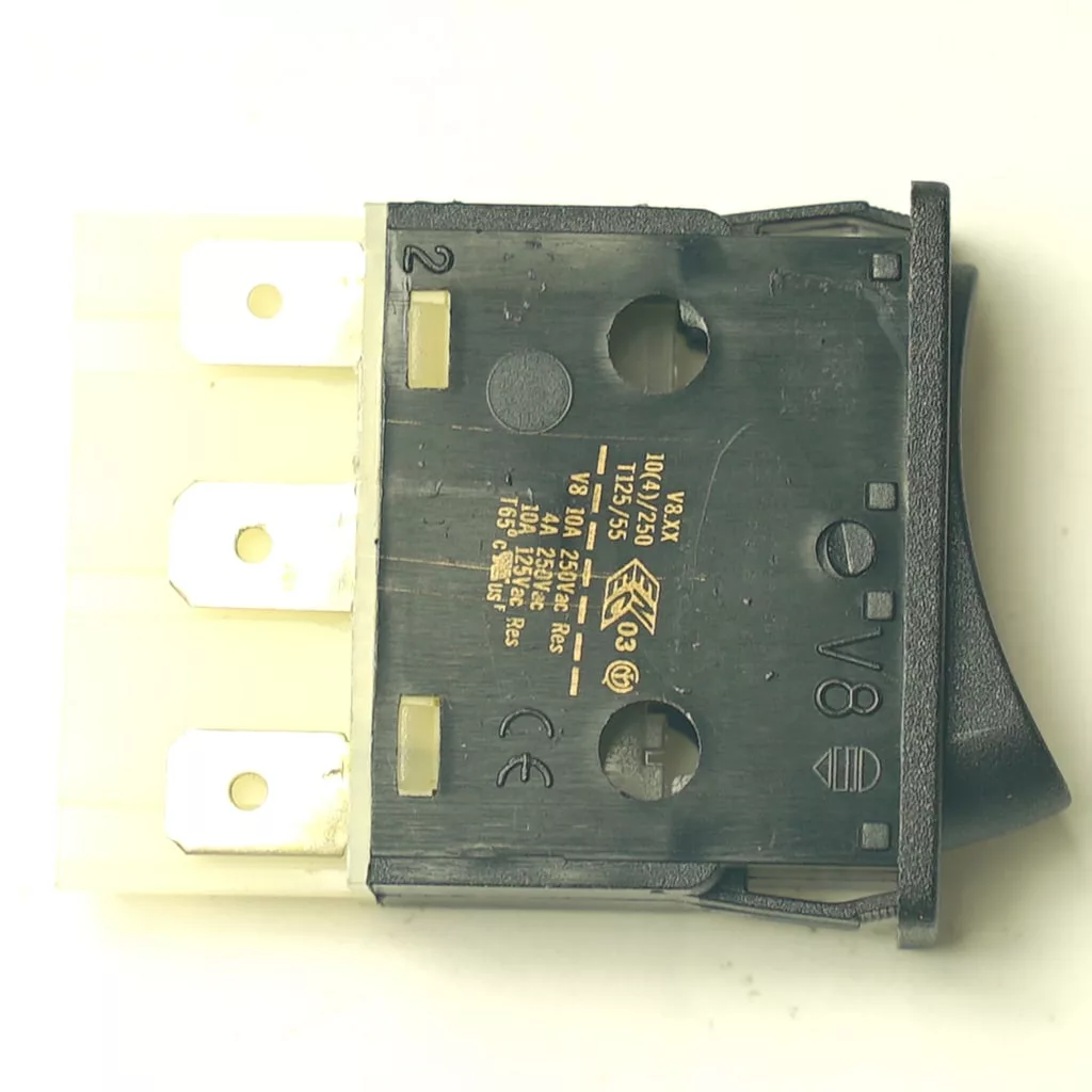 V.4356 GREEN LIGHT ROCKER SWITCH shown from the back on a white background, featuring black and white housing, three metal prongs, green indicator light, and product info with certification symbols printed on the surface. © 2025 1st-line.com