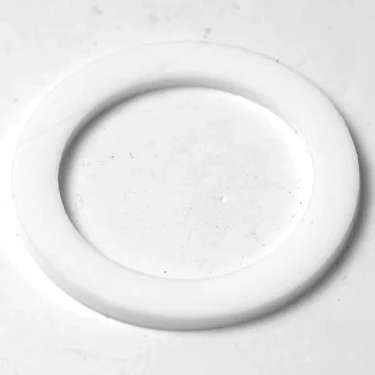 A close-up of a white, flat washer—used to seal connections in the F.1402 FAEMA E-91/DUE Stainless Steel Steam Wand—lying on a smooth, light-colored surface. © 2025 1st-line.com