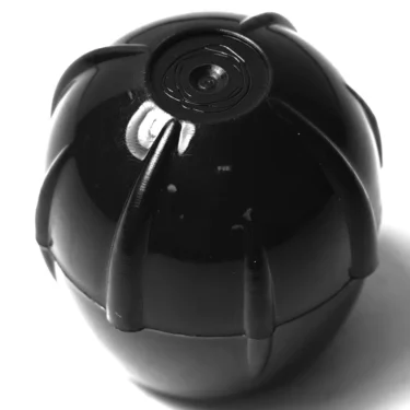 A close-up of the GI.765 STEAM HANDLE, a black, round device with a segmented, claw-like shell, photographed against a white background and resembling a futuristic gadget. © 2025 1st-line.com