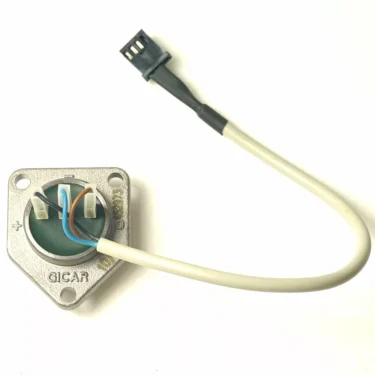 The F.1292 FAEMA FLOWMETER LID is a circular electronic sensor with a metal mounting plate, blue and brown wires, and a white cable ending in a small black connector, shown on a white background. © 2025 1st-line.com