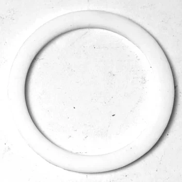 The Gaggia PTFE Heating Element Gasket 50x40x2mm is a smooth, plain white circular ring with uniform thickness, shown lying flat on a lightly textured surface. © 2025 1st-line.com