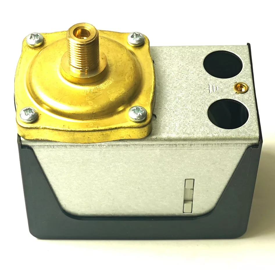 The Magister MAG180023 Pressure Switch features a rectangular gray and black casing, brass top fitting, and two circular side openings, displayed against a white background. © 2025 1st-line.com