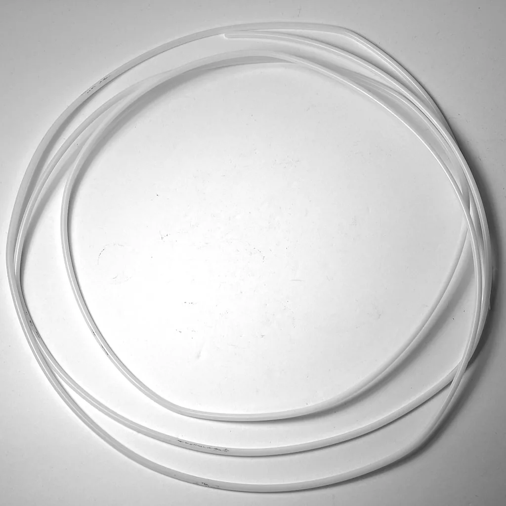 The SM.179 1/4 PTFE PIPE - 1m is a clear, flexible tube coiled loosely in a circle on a plain white surface. © 2025 1st-line.com