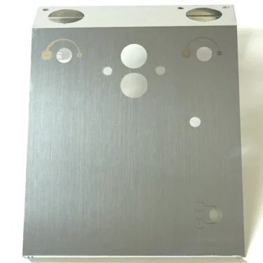 The VBM FRONDOMSJUNV2 FRONT PANEL- DOMOBAR JUNIOR features a brushed metal finish with circular cutouts and engraved symbols for buttons or dials, plus small icons in the corners, all set against a plain white background. © 2025 1st-line.com