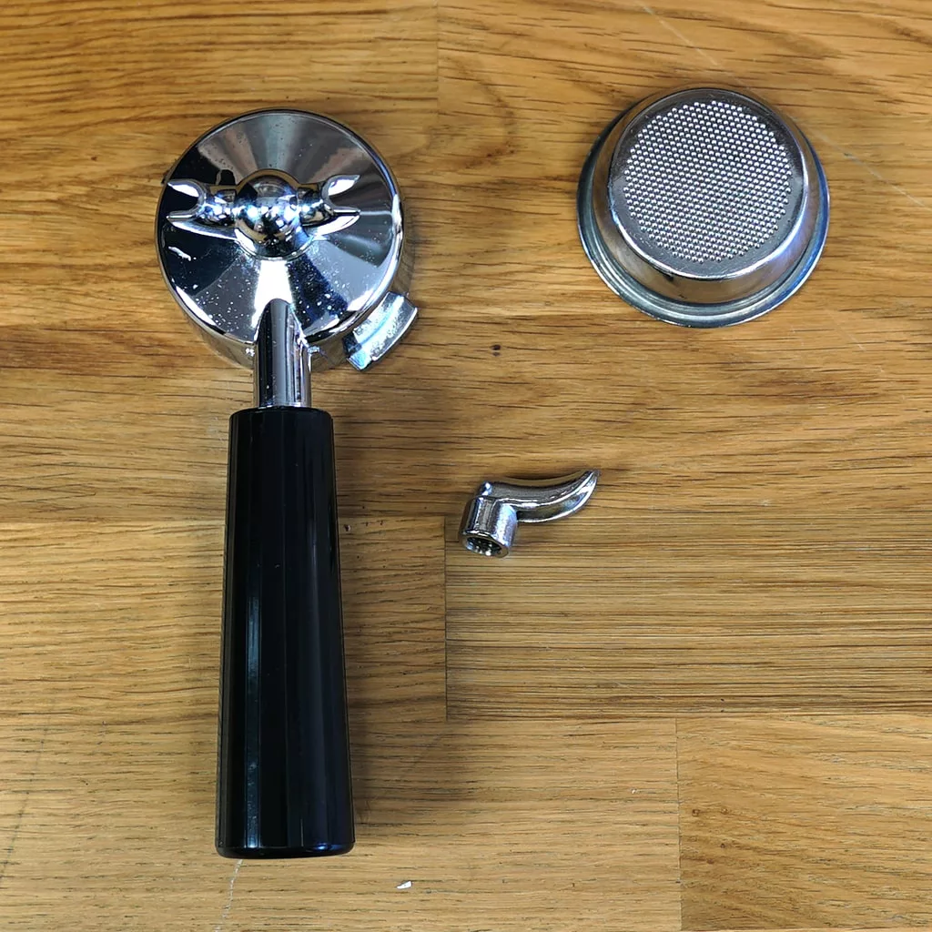 Parts from the SIDEWALK SALE - GEE Digital Espresso Coffee Machine (E213)—including a metal portafilter with black handle, filter basket, and metal spout—are displayed separately on a wooden surface, ready for use. © 2025 1st-line.com