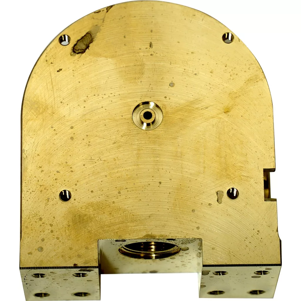 Close-up of an Elektra 05906014 Delivery Group Body brass component with a semi-circular top, four screw holes, central circular indentation, dark stains, rectangular bottom cut-out, and visible wear and machining marks. © 2025 1st-line.com