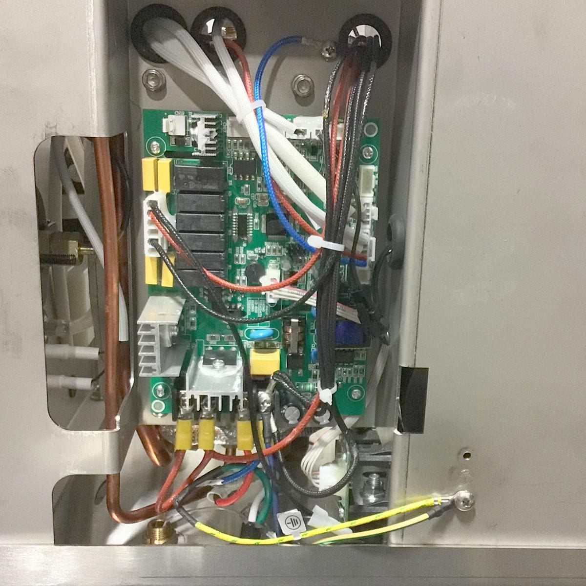 Close-up of the open control panel inside a Bellezza Inizio R Leva HX Espresso Machine, showing a green circuit board with components, relays, and colorful wires in a metal enclosure—crucial for precise machine operation. © 2025 1st-line.com