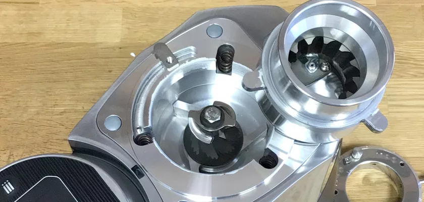 Close-up of the internal burrs and grinder mechanism of the Mazzer Kony S Time-Based Commercial Espresso Coffee Grinder, featuring exposed shiny metal parts on a wooden surface. © 2025 1st-line.com