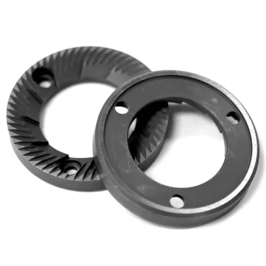 Two black, circular Lelit 1600030 64mm flat grinding burrs with sharp, angled grooves and three holes in each, overlapping on a white background. These are typically used as grinder burrs for coffee grinders. © 2025 1st-line.com
