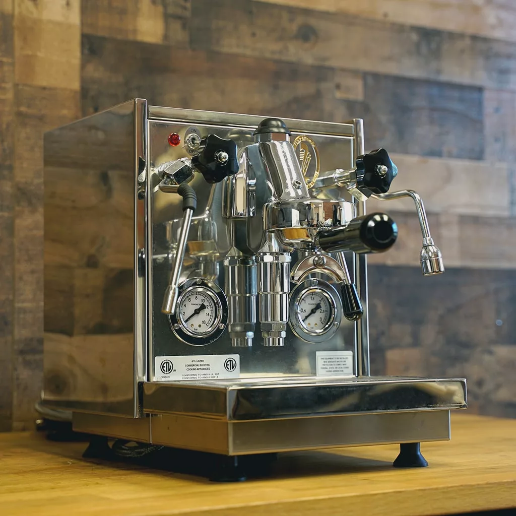 A SIDEWALK SALE - Fiorenzato Volante Direct Connect HX Espresso Machine (E214) with gauges, knobs, and levers sits on a wooden countertop in front of a rustic wood-paneled wall. © 2025 1st-line.com