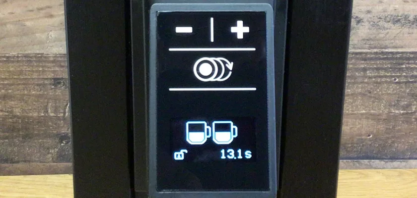 Close-up of the Macap Leo 55 Espresso Coffee Grinder display with plus/minus buttons, a circular icon, two cup icons, and a timer at 13.1 seconds, set against a wooden surface background. © 2025 1st-line.com