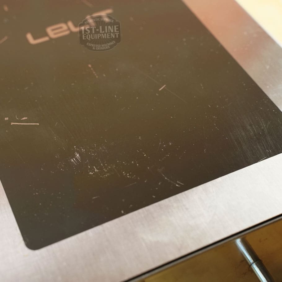 A close-up of the SIDEWALK SALE - Lelit PLA360M Knock Box Drawer (E208) shows its stainless steel surface with a black rectangular section, visible scratches, and a faint reflection of the 1st-Line Equipment logo at the top. © 2025 1st-line.com