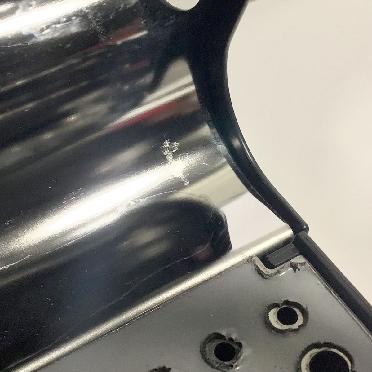 A close-up of the SIDEWALK SALE VBM Domobar Junior Digital HX Espresso Machine w/ Flow Control (OPEN BOX) (E014), showing a shiny curved surface with a small scratch and screw holes near the flow control area. © 2025 1st-line.com