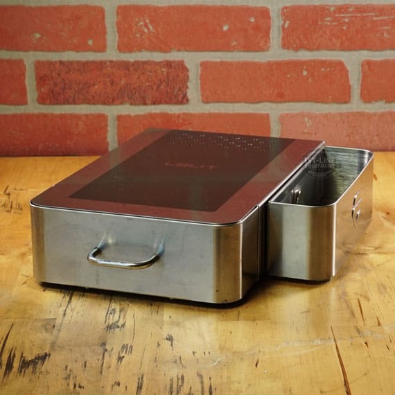 A SIDEWALK SALE - Lelit PLA360M Knock Box Drawer (E208) in stainless steel and black, with a sturdy handle and partially open side drawer revealing its metal interior, sits on wood before a brick wall. © 2025 1st-line.com