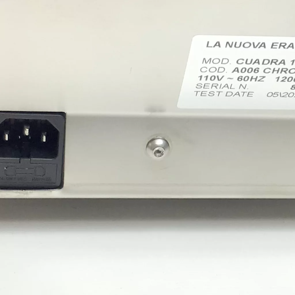Close-up of a Cuadra device’s back panel, highlighting access points for accessing the inside, including a power connector, metal screw, and a white label with LA NUOVA ERA CUADRA 1 model information such as voltage and serial number. © 2025 1st-line.com