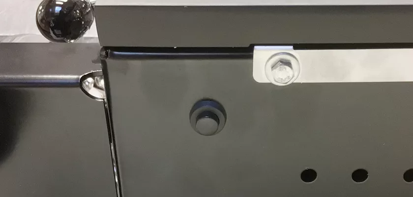 Close-up of the black metal surface on the Rocket Mozzafiato Cronometro Type V HX Espresso Machine, showing a round black knob, a bolt with white washer, and a shiny metallic sphere in the upper left corner. © 2025 1st-line.com