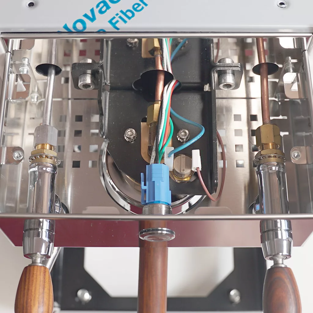 Close-up view of the internal components of a machine, showing copper pipes, wires, and connectors, with part of a label reading “Nova” and a Bezzera Crema sticker visible at the top edge. © 2025 1st-line.com