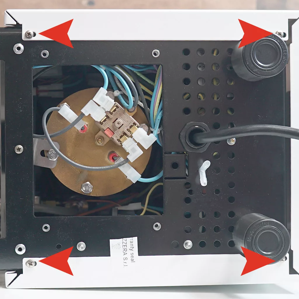 The underside of a Bezzera Crema DE machine with its panel partially removed, showing internal wiring and components. Four red arrows point to screws at each corner of the panel. © 2025 1st-line.com