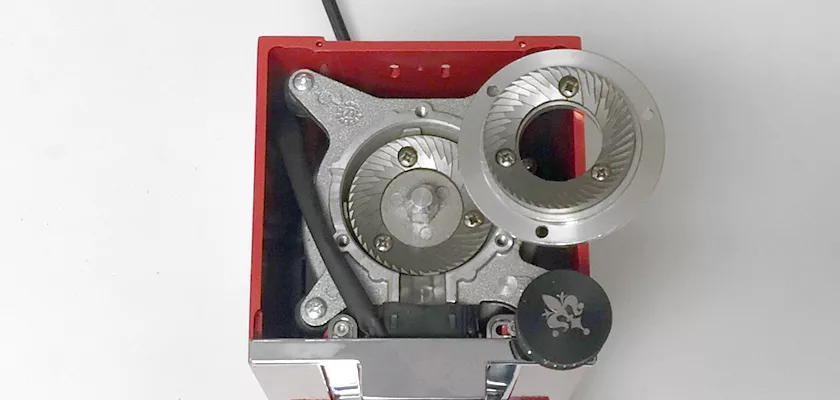 Top view of the Eureka Mignon Libra Espresso Coffee Grinder - Weight-Based Grinding, showing exposed metal burrs and gears. A skull logo knob appears at the lower right, with red and silver casing highlighting its precision. © 2025 1st-line.com