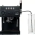 A black Bellezza Bellona Dual Boiler Espresso Machine features control buttons, a steam wand, a pressure gauge, and an external clear water reservoir connected by a tube. © 2025 1st-line.com