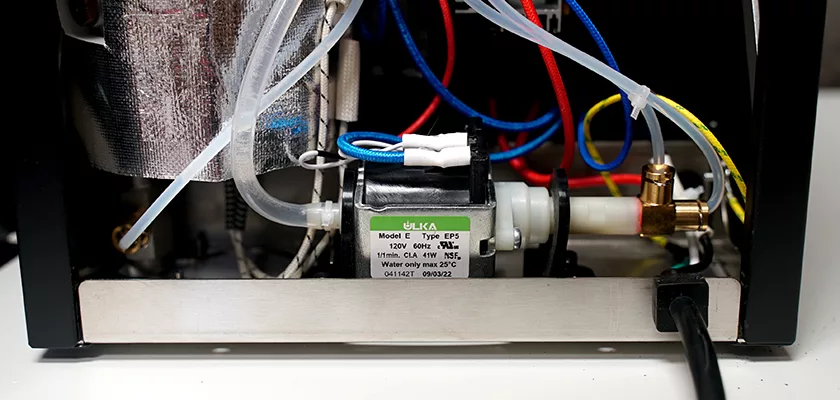 Close-up of the interior of the Bellezza Bellona Dual Boiler Espresso Machine, showing colored wires, clear tubes, and a ULKA Model E Type EP5 pump—all mounted on a sturdy metal frame. © 2025 1st-line.com