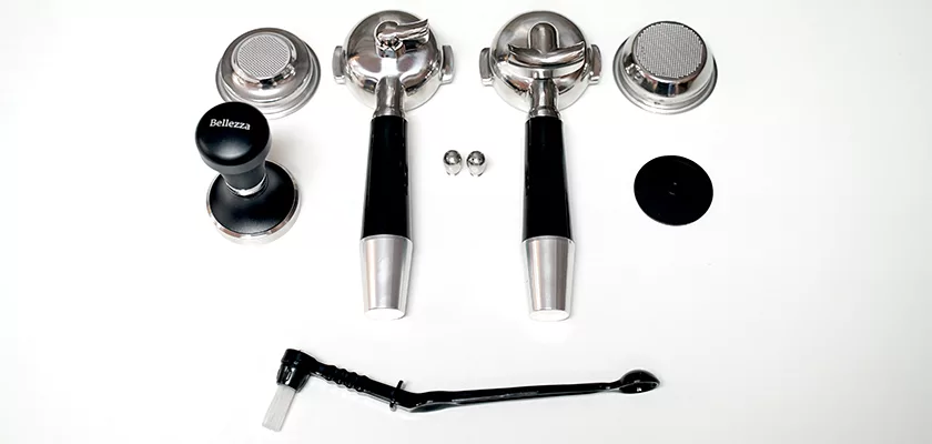 Espresso machine accessories compatible with the Bellezza Bellona Dual Boiler, displayed on a white surface: two portafilters, filter baskets, tamper, screws, cleaning brush, and a black circular accessory. © 2025 1st-line.com