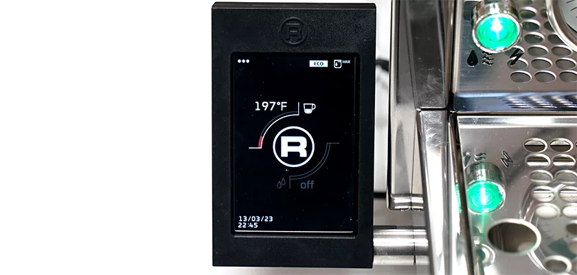 Close-up of the digital touchscreen on the Rocket R Cinquantotto (R58) Dual Boiler Espresso Machine displaying 197°F, a cup icon, and status indicators, with metallic parts and green lights in the background. © 2025 1st-line.com