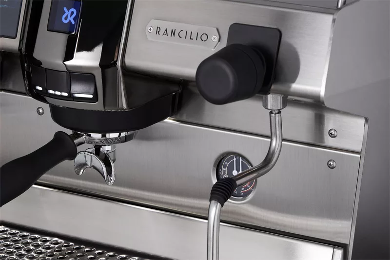 Close-up of the Rancilio Invicta 2 Group Commercial Espresso Machine, featuring a portafilter, steam wand, pressure gauge, and the Rancilio brand name on the front. © 2025 1st-line.com