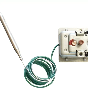 The Bezzera 7434001 Manual Thermostat features a metallic temperature controller with a coiled green wire and metal probe on a rectangular base plate, shown isolated on a white background. © 2025 1st-line.com