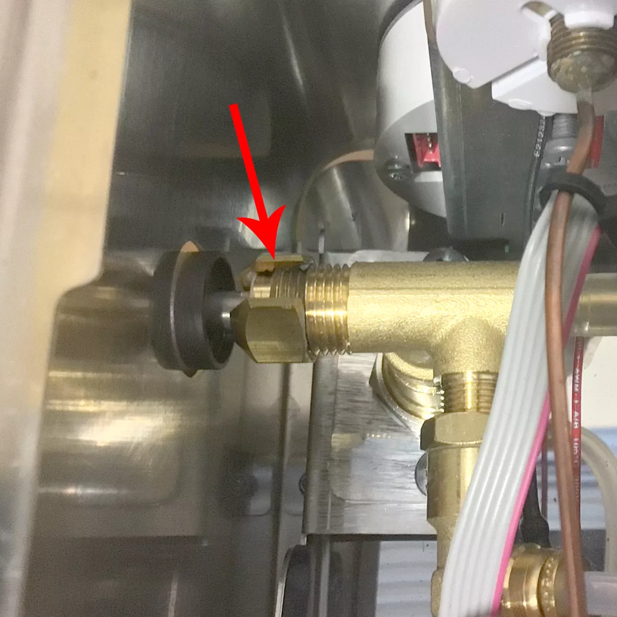 Close-up of metal plumbing with a red arrow pointing at a brass fitting—possibly related to a steam valve stem replacement—connected to a pipe inside a Lelit Elizabeth or Lelit Victoria espresso machine. © 2025 1st-line.com