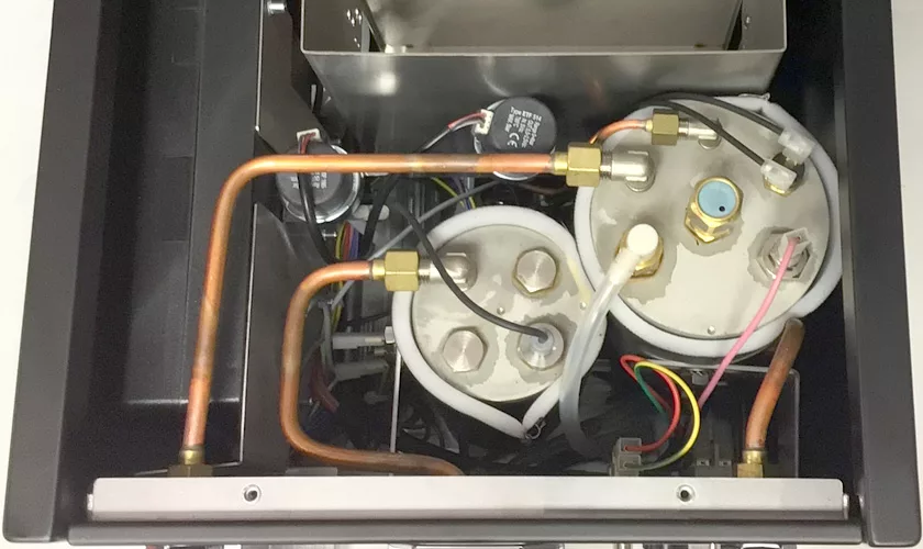 Close-up view of the interior of the Torre Peppina EVO Premium V1 Dual Boiler Espresso Machine w/ FC, highlighting copper pipes, white water tanks, electrical wires, connectors, and other internal mechanical components. © 2025 1st-line.com