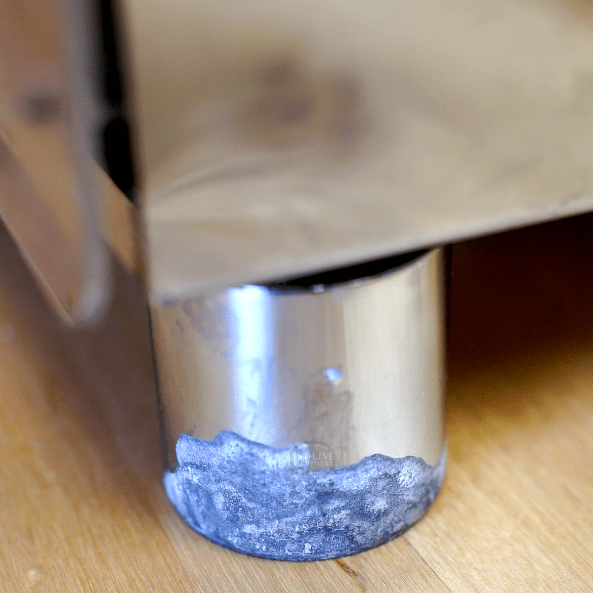 A close-up of a SIDEWALK SALE – VBM Super Electronic Dual Boiler Espresso Machine - direct connect only (E114) leg shows white corrosion or mineral buildup at the base, placed on a wooden floor. © 2025 1st-line.com