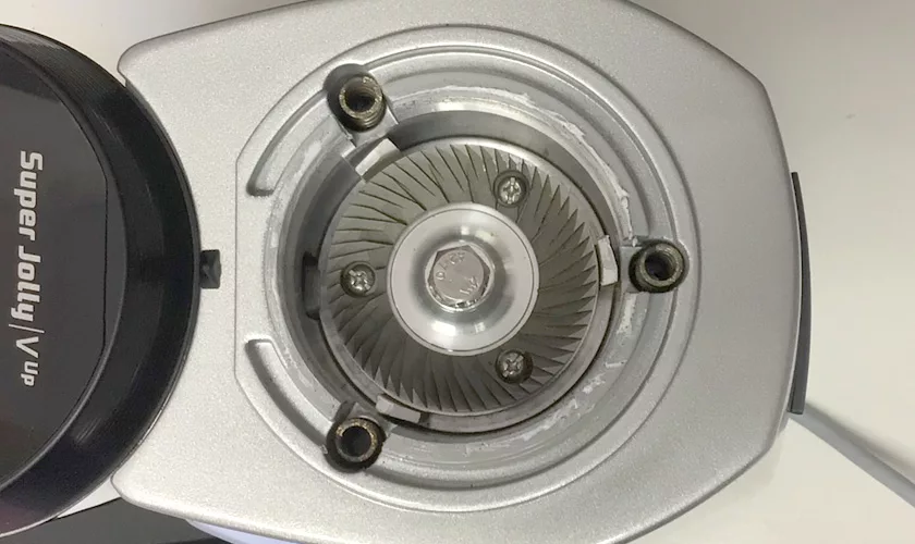 Close-up of burrs inside a Mazzer Super Jolly V UP Espresso Coffee Grinder, showing three visible screws and sharp metal teeth in a circular pattern. The grinders side is labeled Super Jolly V UP. © 2025 1st-line.com