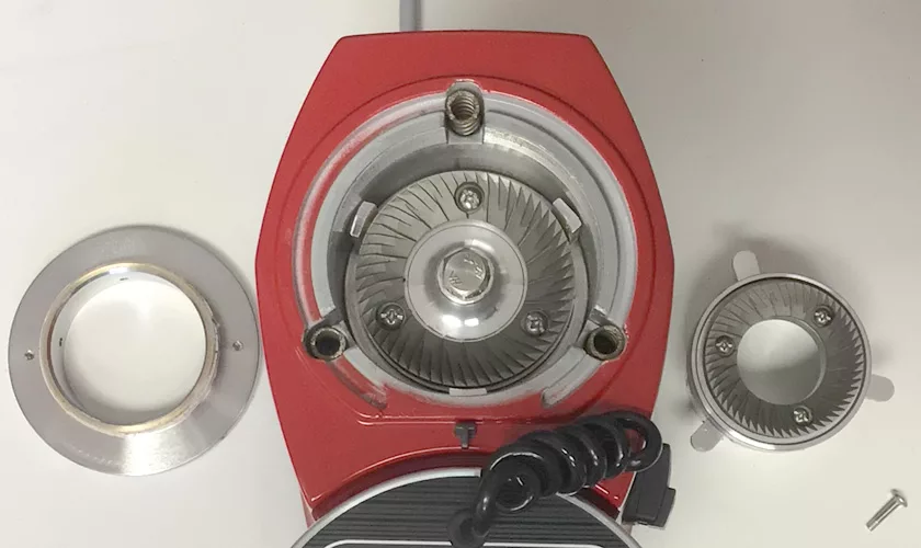 Top view of a red Mazzer Mini A Electronic Time-Based Espresso Coffee Grinder with the burrs and mounting ring removed and placed nearby on a white surface, exposing the inner grinding mechanism and components. © 2025 1st-line.com